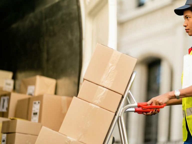 Person using a hand trolley to move stacked cardboard boxes. Person using a hand trolley to move stacked cardboard boxes.