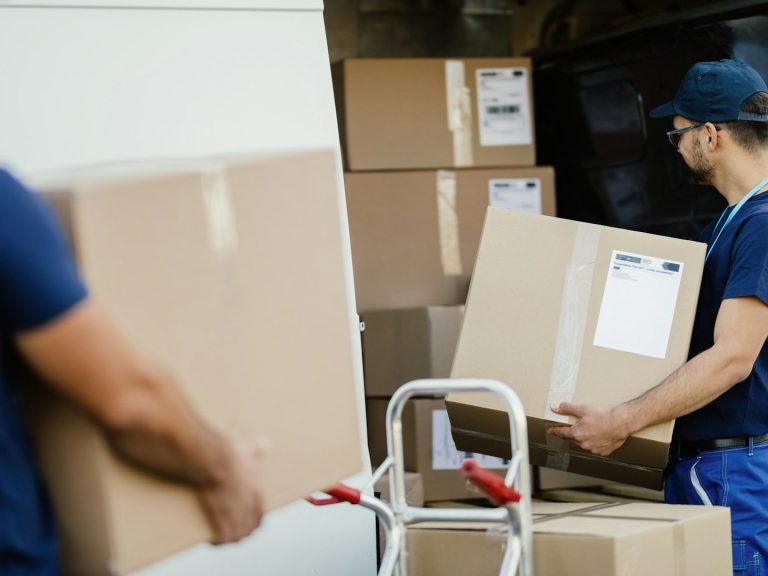 Two workers loading large cardboard boxes from a van. Two workers unloading large cardboard boxes from a van.